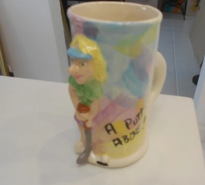 A PUTT ABOVE! WOMAN NOVELTY GOLF 1996 MUG 5 1/2" TALL SIGNED RAISED IMAGE - Image 1 of 4