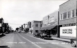 1953 RPPC Postcard LOOKING WEST ONTONAGON. MICHIGAN POLICE CAR, DANCING, BOWLING - Picture 1 of 2