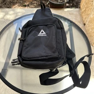 Bolso bandolera de nailon Reebok negro para hombre y mujer. POSICIONES DE TRANSPORTE ÚNICAS - Imagen 1 de 7