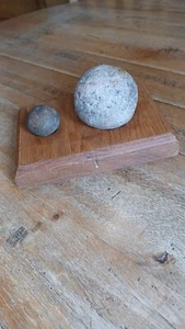 Balas de cañón de piedra en un zócalo de madera - Imagen 1 de 5