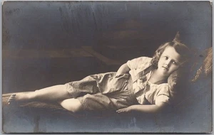 Foto alemana de la década de 1910 RPPC felicitación postal niña en pantalones de cuero a rayas - Imagen 1 de 2