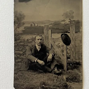 Antique Tintype Photograph Handsome Young Man Sitting On Ground Prop Fence Hat - Picture 1 of 8