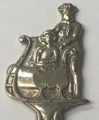 Cuchara de recuerdo vintage coleccionable hombre empujando a mujer en trineo Foto 1 de 3
