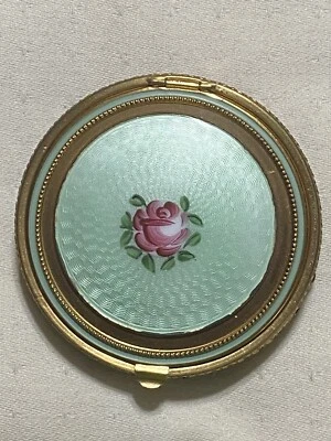 Polvo de esmalte guilloche verde antiguo vintage compacto con etiqueta y fondo de malla dorada Foto 1 de 4