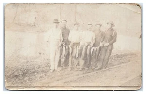Postal RPPC de seis hombres con doce peces en una cuerda - Imagen 1 de 2