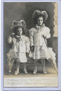 Echt Foto Postkarte RPPC - Weihnachtsgrüße Mädchen in ausgefallener Kleidung Mütze Sonnenschirm - Bild 1 von 2