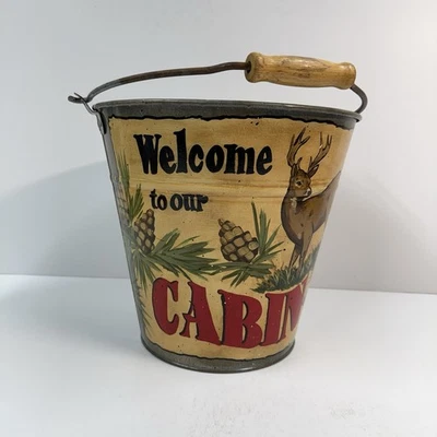Cubo de hojalata bienvenido a nuestra cabaña montaña o lago decoración pintada a mano con piñas Foto 1 de 4