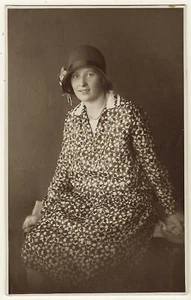 EINE HÜBSCHE JUNGE FRAU IM DRUCKKLEID UND EINER CLOCHE-MÜTZE - Bild 1 von 2