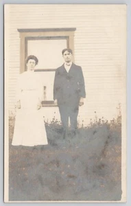 Cartolina fotografica reale coppia in piedi davanti alla finestra RPPC - Foto 1 di 2