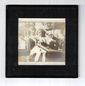 Foto antigua de los años 1900-1910 de mujer y niño en regazo mirando álbum, helechos, palmeras - Imagen 1 de 2