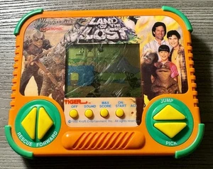 Land of the Lost Tiger Gioco Portatile da Viaggio Elettronico LCD - Testato - Foto 1 di 8