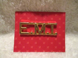 "De colección~E.M.T.~Pinback~Color tono dorado~1,5"" x 0,50" - Imagen 1 de 9