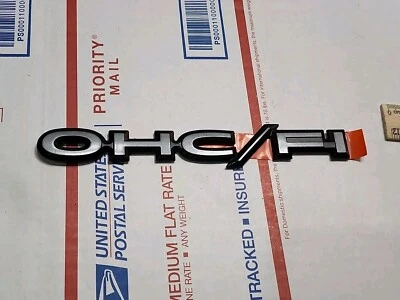 NOS 1982-91 Pontiac Sunbird J2000 前挡泥板 OHC/FI 徽章徽章银色新品 — 第 1/4 张图片