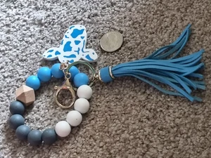 BRACCIALE PORTACHIAVI PERLINE SILICONE BIANCO E BLU CON CIONDOLO MUCCA E NAPPA BLU - Foto 1 di 3