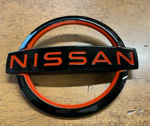 NUEVO FABRICANTE DE EQUIPOS ORIGINALES 2022-2024 EMBLEMA DE PUERTA TRASERA NISSAN FRONTIER - ACENTO ROJO - Imagen 1 de 4