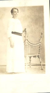 Frau stehend am Stuhl langes weißes Kleid mit Gürtel 1912 RPPC Echtfoto Postkarte - Bild 1 von 2