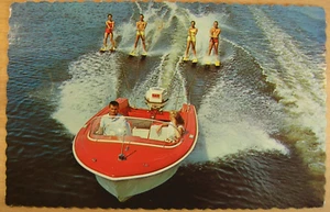 #11 – 1960s low altitude aerial view of lake ski boat pulling 4 skiers on duals - Picture 1 of 4