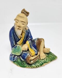 Chinese mudman figurine. Blue and yellow robe, sitting on green leaf