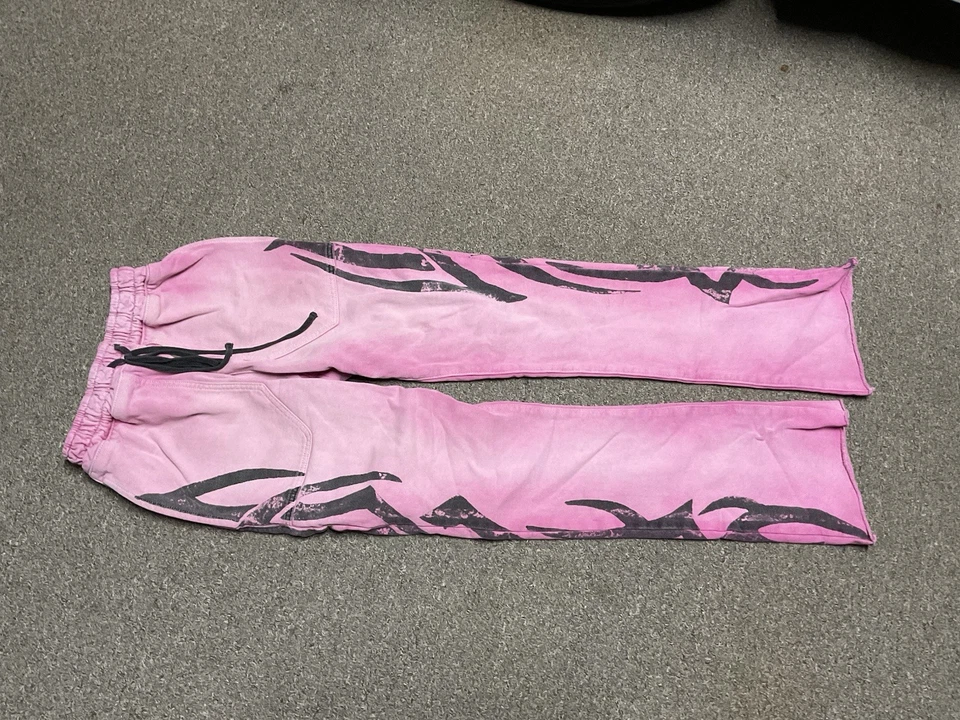es un par de pantalones deportivos Golden Flame en rosa con un gráfico de llama negra Foto 1 de 3