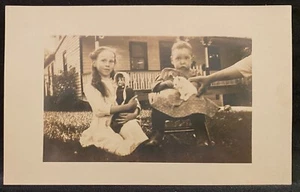 Cartolina fotografica reale RPPC due bambine bambola e gattino bianco tenuto dalla mano della mamma - Foto 1 di 3