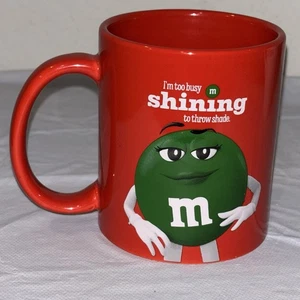 Kaffeebecher M&M 2024 rot mit grün M&M "I'm too busy shining to throw shadow" - Bild 1 von 4