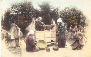 Postal coloreada a mano aldeanos japoneses tamizando arroz en una máquina de aventar - Imagen 1 de 2