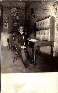A GENTLEMAN WORKING AT HIS DESK : POSTCARDS & PHOTOS ON THE WALL : RPPC - Picture 1 of 5