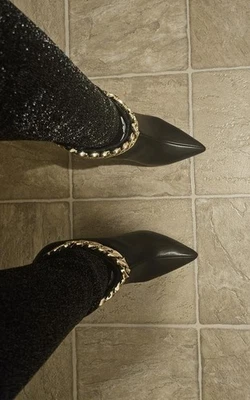 Grueso tono dorado cadenas ribete un chic par de tacones de aguja puntiagudos en los botines Foto 1 de 4