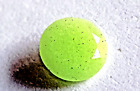 Pierre précieuse à facettes verte lumineuse coupe ronde, brillante dans une pierre précieuse sombre, forme ronde