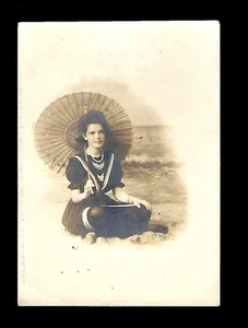 RPPC de principios de 1900, mujer joven bajo el paraguas en la playa - Imagen 1 de 2