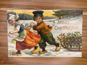Christmas Children joyous Christmastide-Dutch boy & girl pulling sled with holly - Picture 1 of 2