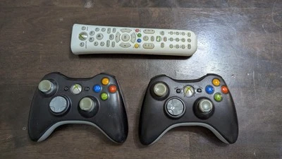 Xbox 360: Two Black Wireless Controllers and One White Remote READ DESCRIPTION - Image 1 of 4