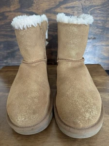 Botas Cortas UGG Bailey Bow Dorado Brillante Castaño Piel de Oveja Para Mujer Talla 8” - Imagen 1 de 15