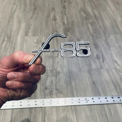 1964-1965 OLDSMOBILE F-85 GUARDABARROS EMBLEMA INSIGNIA OEM OLDS GM 7589285 SCRIPT Foto 1 de 4