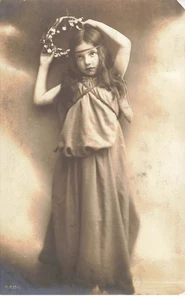 Enfant - Jeune fille se mettant une couronne de fleurs dans les cheveux - Foto 1 di 2