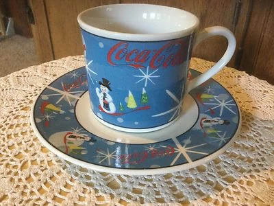 Muñeco de nieve riendo de The Coca Cola Company.  Taza y platillo.  Azul, rojo, blanco. Foto 1 de 4