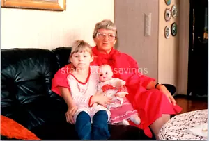 Found Photo - 80s 90s - Little Girl Holds Doll With Smiling Grandma On The Couch - Picture 1 of 2