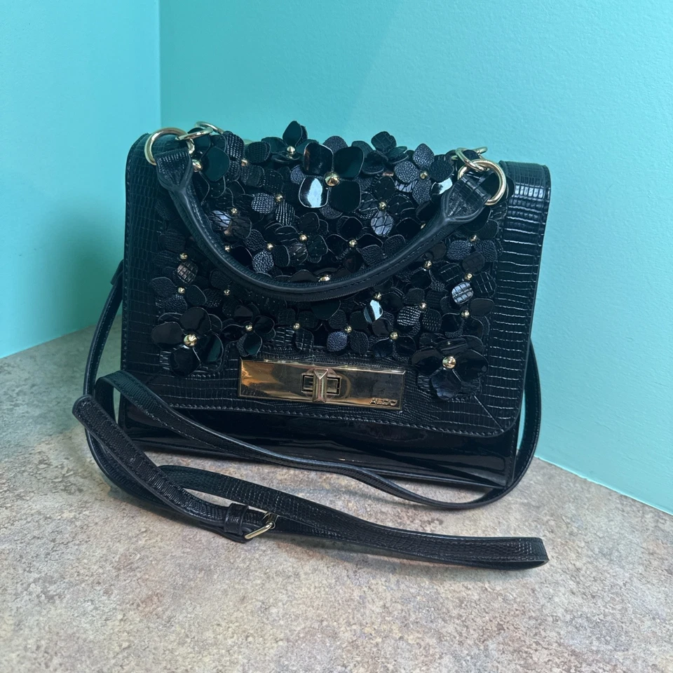 Monedero floral charol negro Aldo, herrajes dorados, tanto muñeca como bandolera  Foto 1 de 4