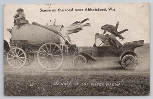 Road Scene Near Abbotsford WI Tall-Tale Exaggerated Postcard Water Wagon Old Car - Picture 1 of 5