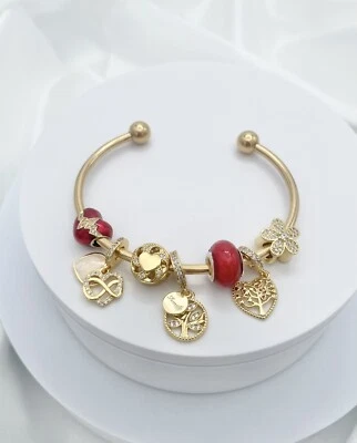 Brazalete abierto Linx oro amarillo con dijes temáticos rojos y dorados Foto 1 de 4