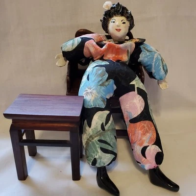 Muñeca asiática con cara de cerámica sentada en silla de madera con mesa de madera Foto 1 de 4