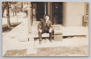 Postkarte RPPC 1900er Jahre Mann sitzt vor einem Hotel. Vielleicht ein Verkäufer? - Bild 1 von 2