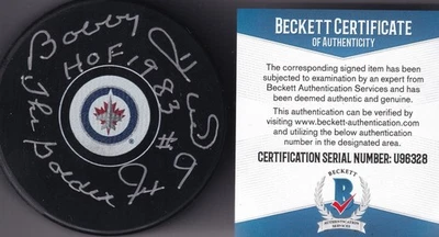 BECKETT BOBBY CASCO "HOF 1983" Y "GOLDEN JET" FIRMADO WINNIPEG JETS PUCK U96328 Foto 1 de 2
