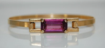 ELEGANTE BRAZALETE CON BISAGRAS AVON COUTURE PIEDRA PÚRPURA SOBRE METAL DORADO Foto 1 de 4