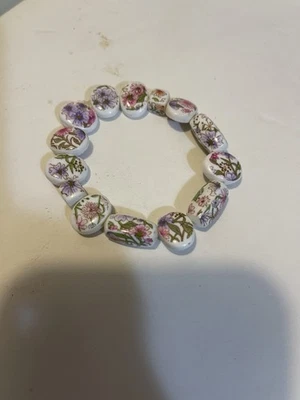 Pulsera elástica hecha a mano con cuentas florales de porcelana en colores pastel sobre blanco Foto 1 de 3