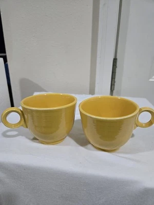 Dos tazas de café Fiesta genuinas vintage de los años 50 amarillas/doradas de H.L. Co. Foto 1 de 4