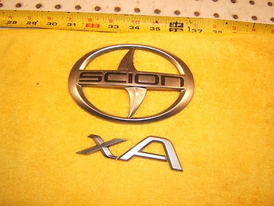 Scion XA 2006 escotilla trasera plástico plata genuino Scion OEM 1 juego de 2 emblemas, XA Foto 1 de 4