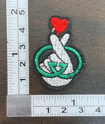 Fingers Holding Red Heart Embroidered Iron On Patch - Image 1 of 2
