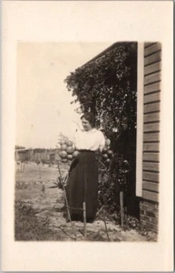 Foto postal real mujer al aire libre c1910s RPPC sosteniendo dos ramos de naranjas - Imagen 1 de 2