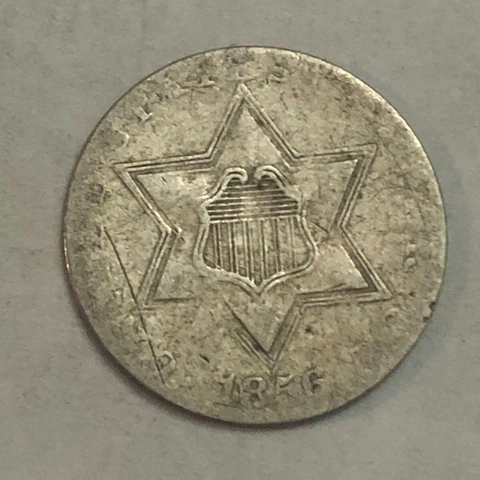 1856 silver U.S. three-cent piece. VG, light scratches. #ed1 Cover